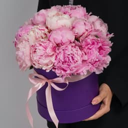 Праздничная композиция из 15 пионов в сиреневой шляпной коробке