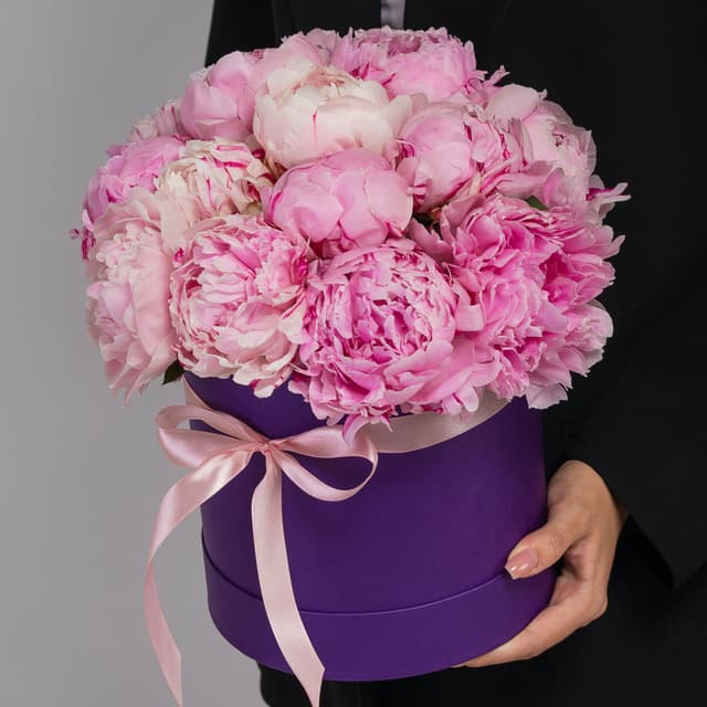 Праздничная композиция из 15 пионов в сиреневой шляпной коробке Праздничная композиция из 15 пионов в сиреневой шляпной коробке
