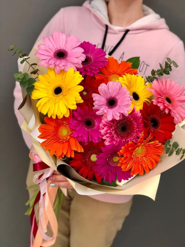 Свежий букет из 15 гербер в матовой бумаге с зеленью Свежий букет из 15 гербер в матовой бумаге с зеленью