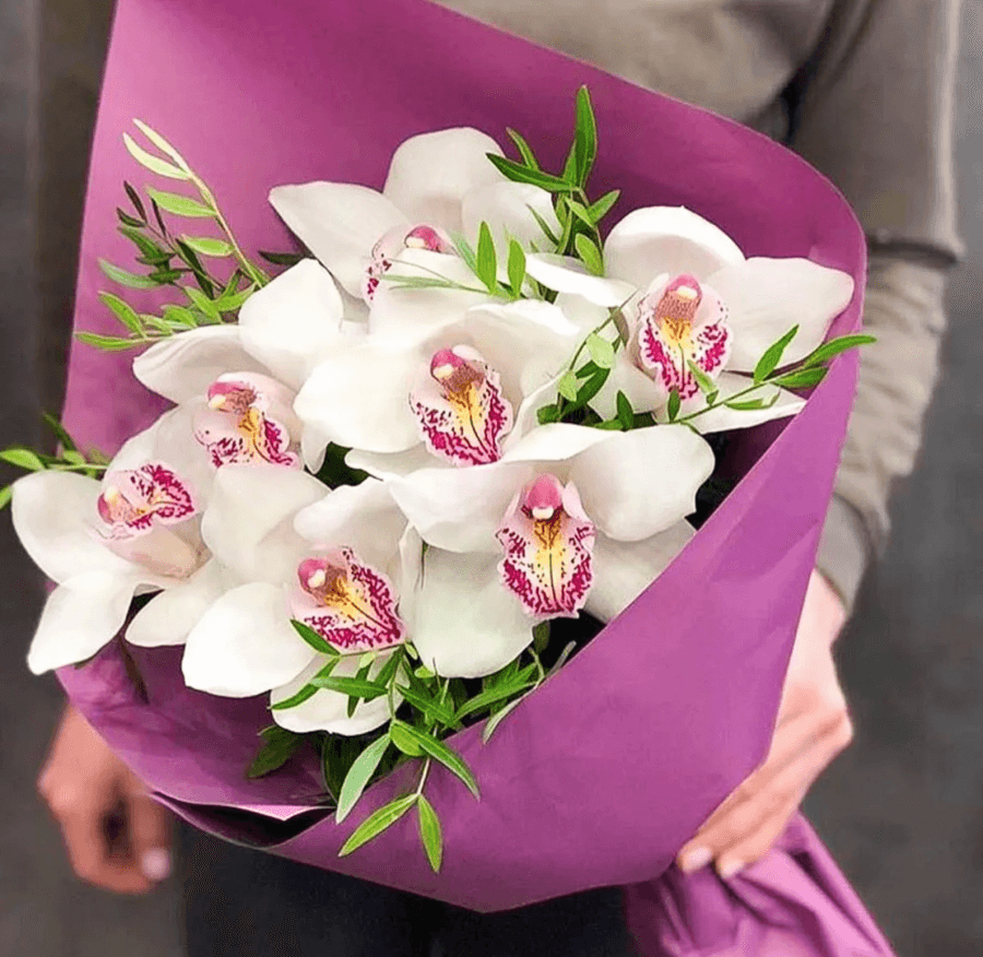 Оригинальный букет из 7 Орхидей в матовой бумаге с зеленью