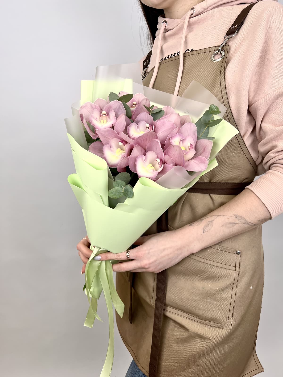 Шикарный букет из 7 розовых Орхидей в матовой бумаге с зеленью