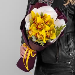 Шикарный букет из 7 желтых Орхидей в матовой бумаге с зеленью